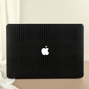 May include: Black laptop case with a crocodile skin pattern and a white Apple logo.