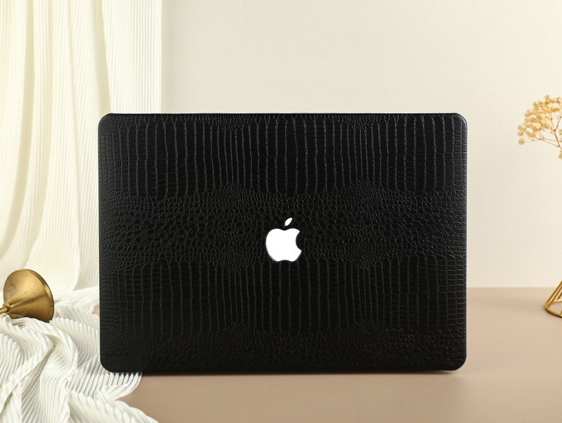 May include: Black laptop case with a crocodile skin pattern and a white Apple logo.