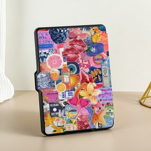 May include: A black e-reader case with a colorful collage design. The design includes images of fruit, flowers, hearts, and other objects. The text on the case includes the words 'FOREVER', 'RIMA', 'GIN', and 'GARDINE'. 