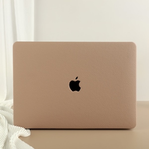 May include: A light brown laptop case with a textured surface and the Apple logo in the centre.