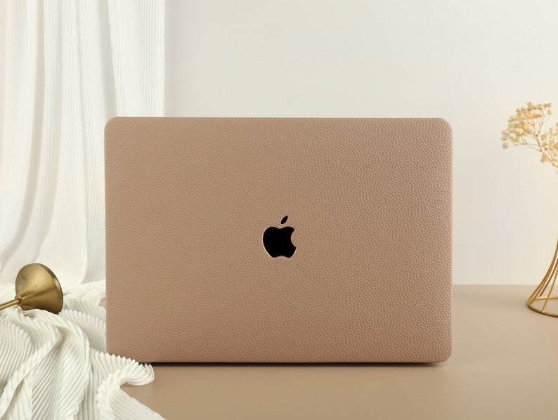May include: A light brown laptop case with a textured surface and the Apple logo in the center.