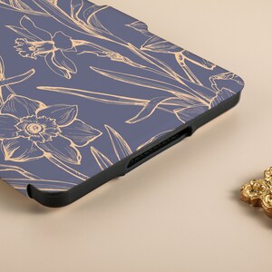 May include: A blue e-reader case with a floral design. The case has a black edge and a pattern of white daffodils on a blue background.