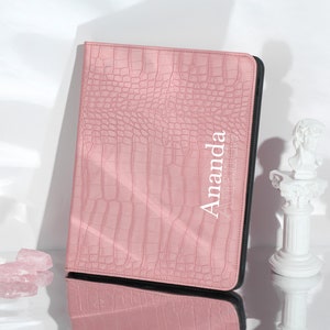 May include: A pink faux leather notebook with a crocodile pattern and the name "Amanda" embossed in white on the front cover.