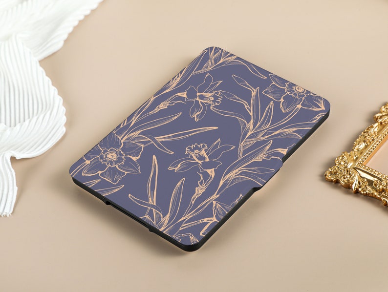 May include: A blue e-reader cover with a floral design featuring delicate, light orange daffodils on a dark blue background.