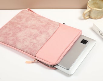 Könnte beinhalten: Eine rosa Laptoptasche mit Reißverschluss und weichem, strukturiertem Äußeren. Die Tasche ist geöffnet und ein silberner Laptop befindet sich im Inneren.