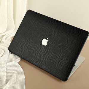 May include: Black laptop case with a crocodile skin pattern and an Apple logo.