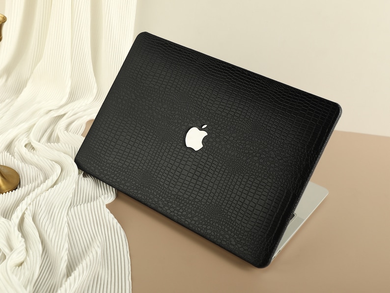 May include: Black laptop case with a crocodile skin pattern and an Apple logo.
