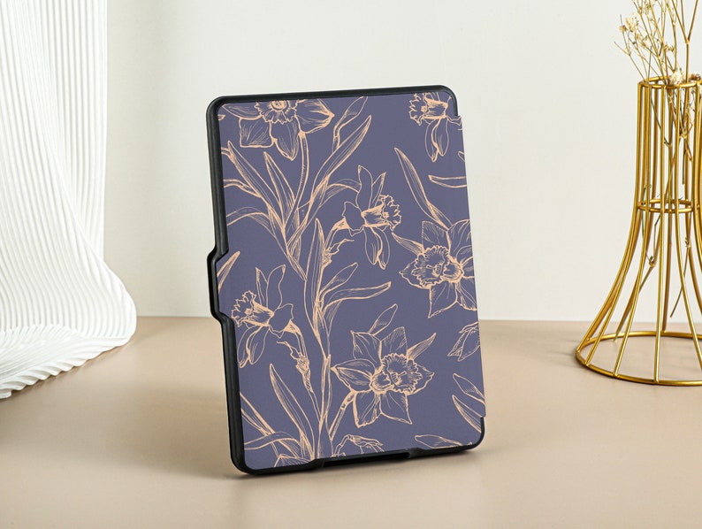 May include: A blue e-reader case with a floral design. The flowers are outlined in a light peach color and are on a dark blue background.