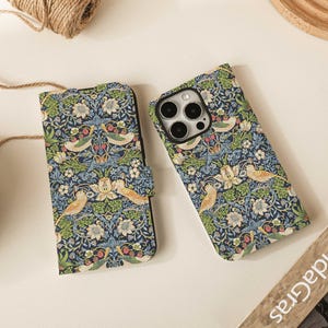 Könnte beinhalten: Zwei Handyhüllen mit einem Blumen- und Vogelmuster in Blau, Grün und Creme. Eine Hülle ist im Folio-Stil mit Magnetverschluss. Die andere ist eine Standard-Handyhülle. Beide haben ein sich wiederholendes Muster aus Vögeln und Blumen.