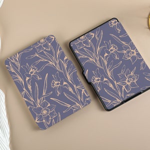 May include: Two purple e-reader cases with a floral design. The design features delicate, light orange daffodils and leaves on a dark purple background.