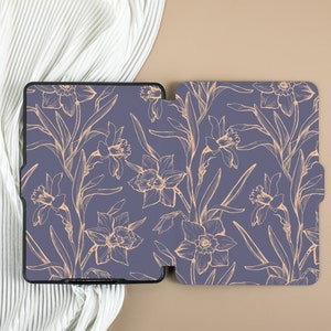 May include: A purple e-reader case with a floral design. The case has a gold outline of daffodils and leaves on a purple background.
