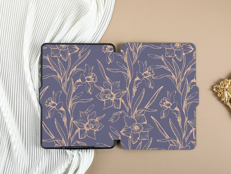 May include: A purple e-reader case with a floral design. The case has a gold outline of daffodils and leaves on a purple background.