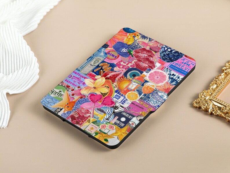 May include: A black e-reader case with a colorful collage design. The design includes images of fruit, flowers, fish, lips, and text such as 'Sprite', 'Gin', 'Rima', 'Sardine', 'Love Forever', and 'New York'. 