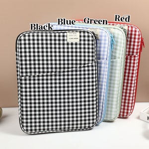 Puede incluir: Cuatro estuches con cremallera en patrones de cuadros vichy negro, azul, verde y rojo. Cada estuche tiene una cremallera y un pequeño bolsillo en la parte delantera.