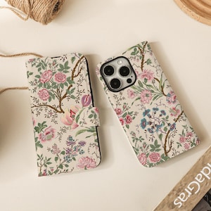 May include: Two floral patterned phone cases. One is a folio style with a magnetic closure, and the other is a standard case. The cases feature a cream background with pink, blue, and green floral designs.