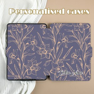 May include: A purple and gold floral patterned case for an e-reader. The case is open and the inside of the case has the text "Custom Name" written in gold.