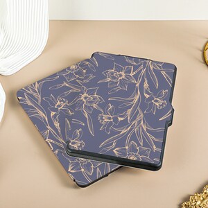 May include: Two blue e-reader cases with a floral pattern. The pattern is of gold daffodils and leaves on a dark blue background.