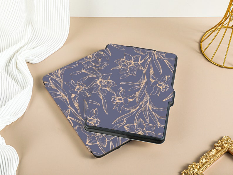 May include: Two blue e-reader cases with a floral pattern. The pattern is of gold daffodils and leaves on a dark blue background.