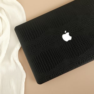 May include: A black laptop computer case with a crocodile skin pattern and a white Apple logo.