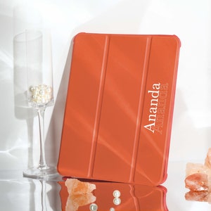 May include: A coral orange tablet case with the name "Amanda" printed in white on the front.