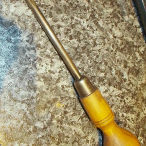 Peut inclure: Un tournevis plat vintage avec un manche en bois et une tige en métal. La poignée est de couleur marron clair et la tige en métal est argentée. Outil à main pour visser ou dévisser.
