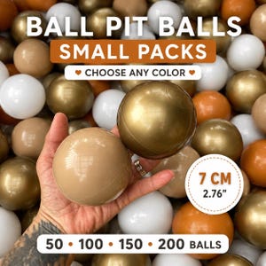 Op de afbeelding: Een verzameling gladde, ronde plastic ballen in de kleuren wit, goud en beige. De ballen hebben een diameter van 7 cm. De afbeelding bevat tekst met BALL PIT BALLS SMALL PACKS, CHOOSE ANY COLOR en 50, 100, 150, 200 BALLS.