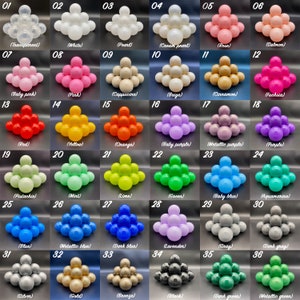 May include: A chart displaying 36 different coloured plastic balls arranged in rows of six. Each ball is labelled with a number and a colour name. The colours include transparent, white, pearl, cream pearl, rose, salmon, baby pink, pink, cappuccino, beige, cinnamon, fuchsia, red, yellow, orange, baby purple, metallic purple, purple, pistachio, mint, lime, green, baby blue, aquamarine, blue, metallic blue, dark blue, lavender, grey, dark grey, silver, gold, bronze, black, dark green, and metallic green.