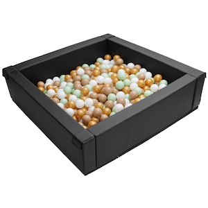 May include: A black square ball pit filled with white, green, and gold plastic balls.