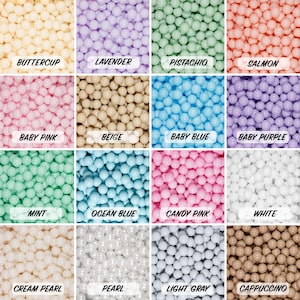 Peut inclure: Une grille de 16 carrés, chacun rempli de billes en plastique de couleur différente. Les couleurs sont : jaune pâle, lavande, pistache, saumon, rose pâle, beige, bleu bébé, violet bébé, menthe, bleu océan, rose bonbon, blanc, perle crème, perle, gris clair et cappuccino.