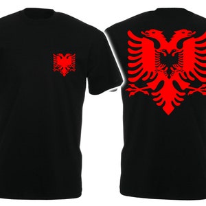 Könnte beinhalten: Schwarzes T-Shirt mit einem roten albanischen Doppelkopfadler, der auf der Rückseite gedruckt ist, und einer kleineren Version des Adlers, die auf der linken Brust gedruckt ist.