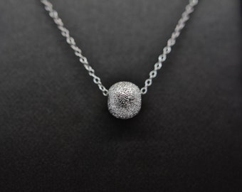 May include: A silver chain necklace with a small, round, silver pendant covered in tiny, sparkling stones.