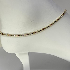 May include: A delicate gold anklet with a single row of colorful rhinestones.