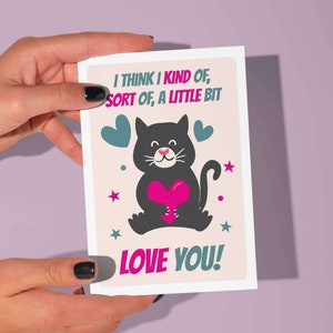Biglietto d'amore stampabile con citazione: "Penso di amarti un po'". Dolce gatto che tiene in mano un cuore. (beige).