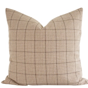 Puede incluir: Una almohada de tiro de cuadros beige y marrón con un patrón cuadrado.