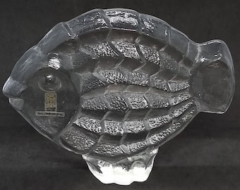 May include: A clear glass sculpture of a fish with a textured surface. The fish is about 6 inches long and 3 inches wide.