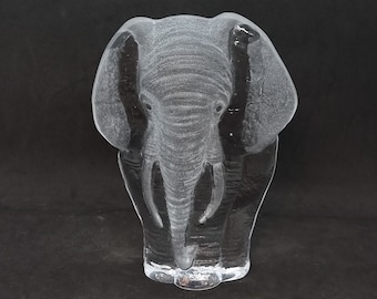 May include: A clear glass sculpture of an elephant. The elephant is standing with its trunk lowered and its ears spread out.