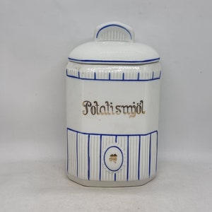 Puede incluir: Un tarro de cerámica blanco con un diseño azul y dorado. El tarro tiene una tapa con asa y dice "Potatismjöl" en letras doradas.