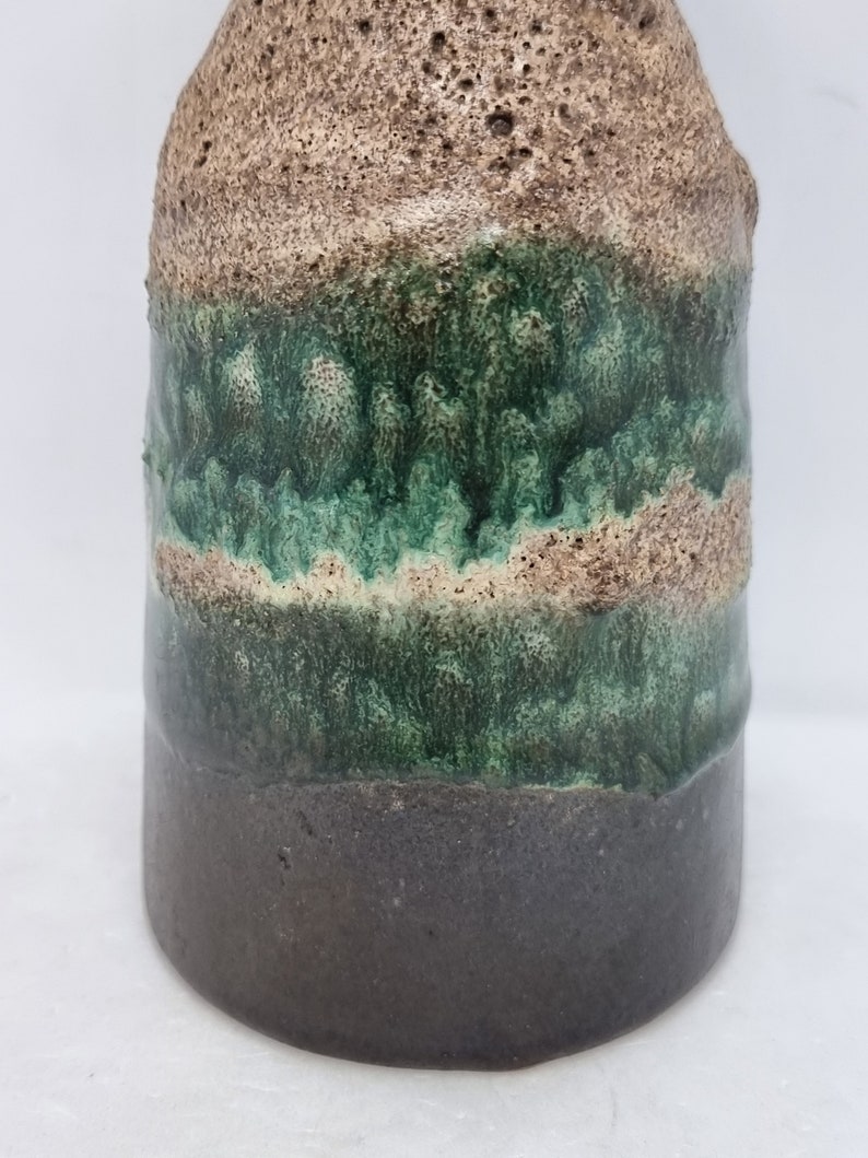 Puede incluir: Un jarr&oacute;n de cer&aacute;mica con un esmalte marr&oacute;n texturizado, una banda de esmalte verde y una base marr&oacute;n oscuro.