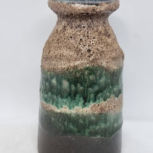 Puede incluir: Un jarr&oacute;n peque&ntilde;o de cer&aacute;mica marr&oacute;n y verde con una superficie texturizada. El jarr&oacute;n tiene una base ancha y un cuello estrecho.
