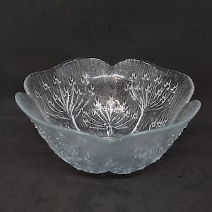 May include: A clear glass bowl with a textured, frosted finish. The bowl has a scalloped edge and features a design of trees etched into the glass.