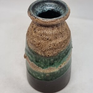 Puede incluir: Un peque&ntilde;o jarr&oacute;n de cer&aacute;mica marr&oacute;n con un esmalte verde y azul. El jarr&oacute;n tiene una superficie texturizada y una boca ancha.