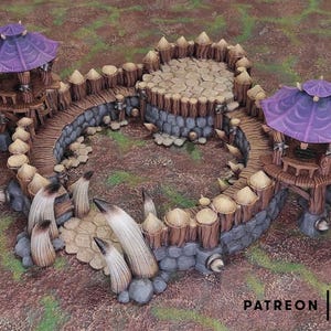 May include: A miniature fantasy fortress with two purple-roofed towers connected by a wooden bridge. The fortress has a stone and wood wall with decorative spikes. The base is surrounded by stylized rock formations.
