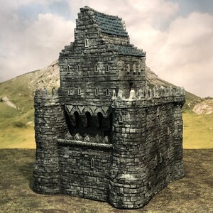 May include: A miniature stone castle in shades of grey and blue. The castle has a multi-level design with small rectangular windows and a crenellated roof. The structure is made of individual stone blocks, creating a textured appearance. The castle is a fantasy-themed item.