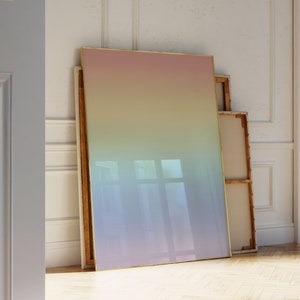 Puede incluir: Un lienzo grande enmarcado con un degradado de colores rosa, amarillo, verde y azul. El lienzo está apoyado contra una pared.