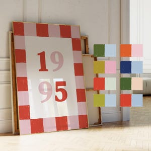 May include: A framed print with a red and pink checkered pattern and the numbers 1995 in the center. The print is on a white background.