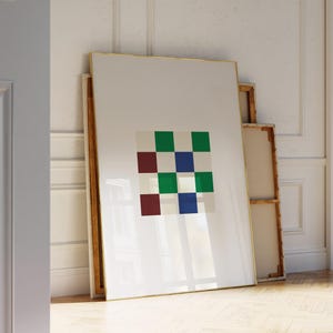 May include: A framed art print with a grid of green, blue, and burgundy squares on a cream backdrop. The artwork is displayed in a room with a wooden floor and white walls.