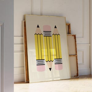 May include: A framed art print featuring three large yellow pencils with black tips and pink erasers. The pencils are arranged vertically against a cream-colored background. The artwork is leaning against a white wall and wooden floor.