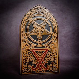 May include: A black and gold leather plaque featuring a pentagram and other occult symbols. The pentagram has a goat's head in the centre.