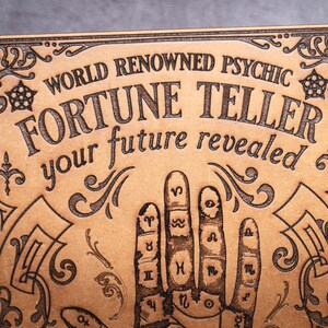 May include: A wooden sign with an ornate border and the text "World Renowned Psychic Fortune Teller your future revealed". The sign features a hand with astrological symbols on the palm.