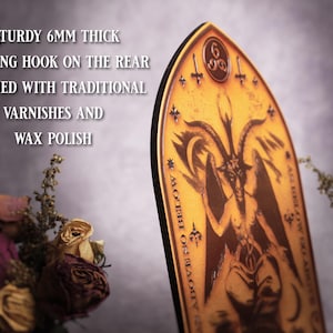 May include: A wooden plaque with a dark brown image of a goat-headed figure with wings and a pentagram. The plaque is 6mm thick and has a hanging hook on the back. The text on the plaque reads "MOTHER OF THE BLACK", "ALL HAIL COW FROM THE VOID", and "666".